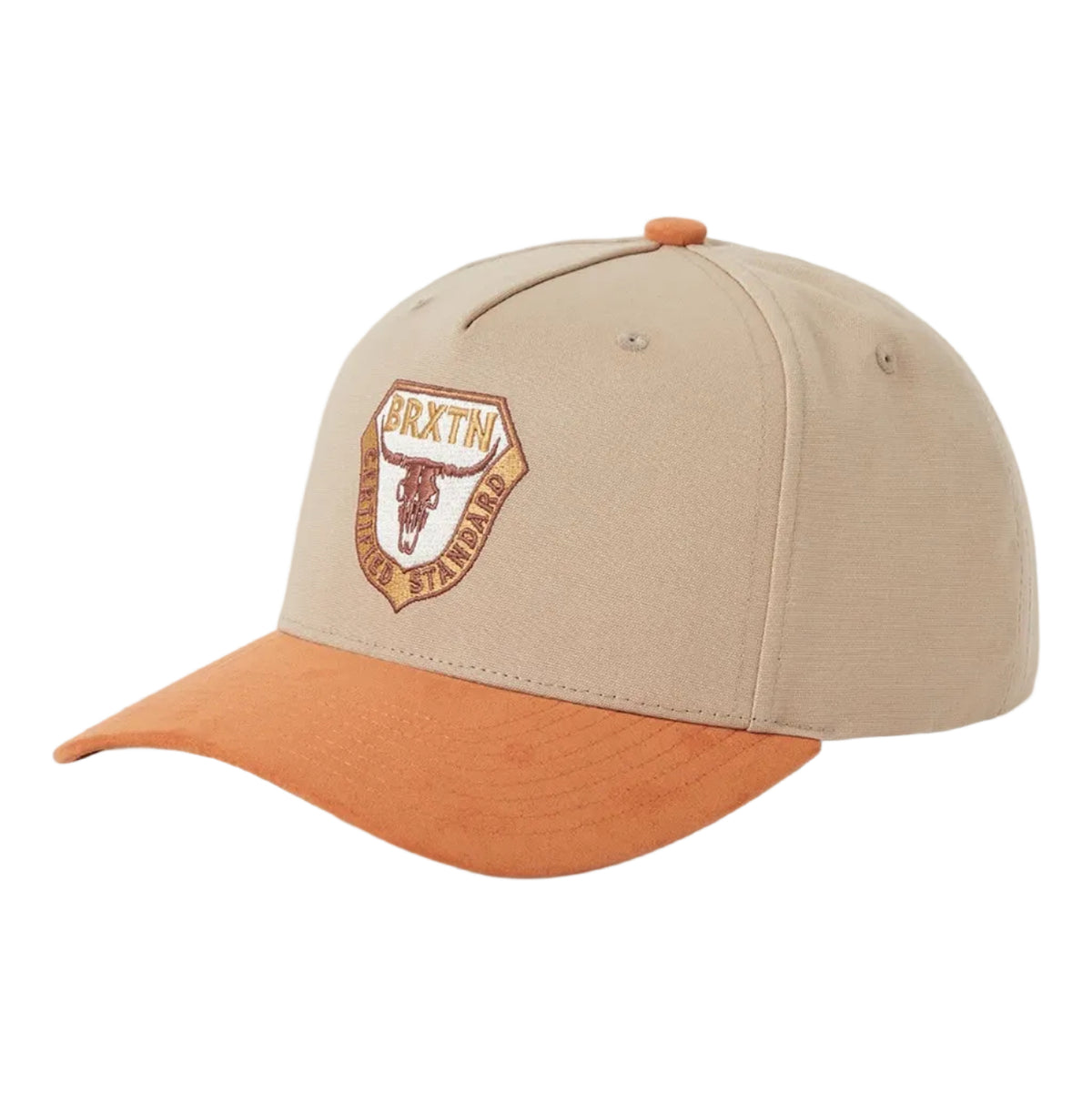 A baseball cap in beige and orange, featuring an embroidered shield logo on the front with the text 'BRXTN Certified Standard" with a bull skull in the middle