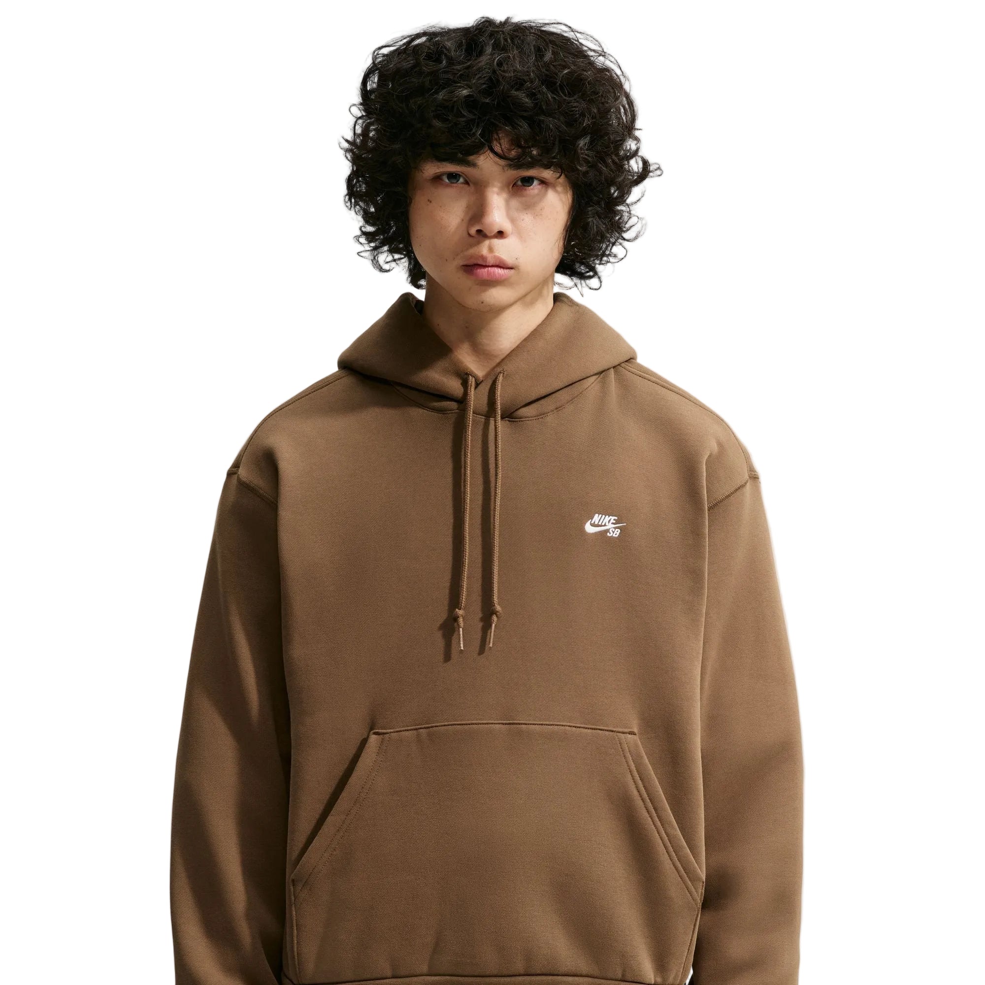 A model with curly black hair wearing a brown Nike hoodie with a small white Swoosh logo on the left chest, set against a solid light gray background.