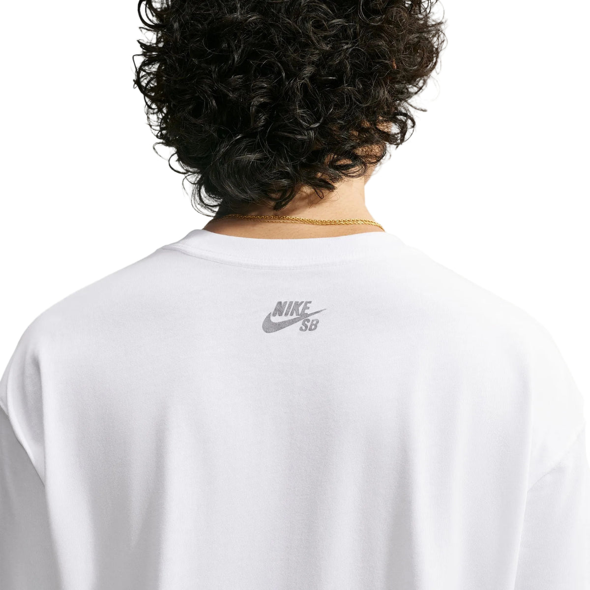 Back view of a person with curly dark hair wearing a white Nike SB t-shirt, showing the gray logo on the upper back against a light off-white background.