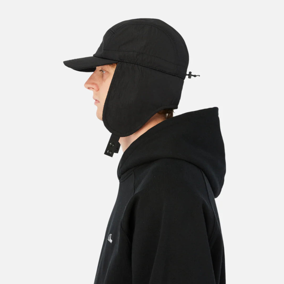 Person wearing a black coat and cap on a white background