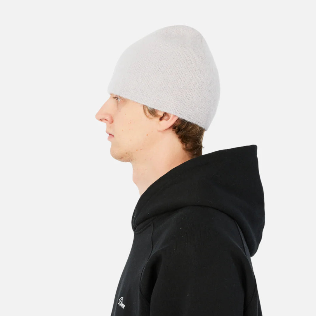 Person wearing a black hoodie and white beanie on a light gray background