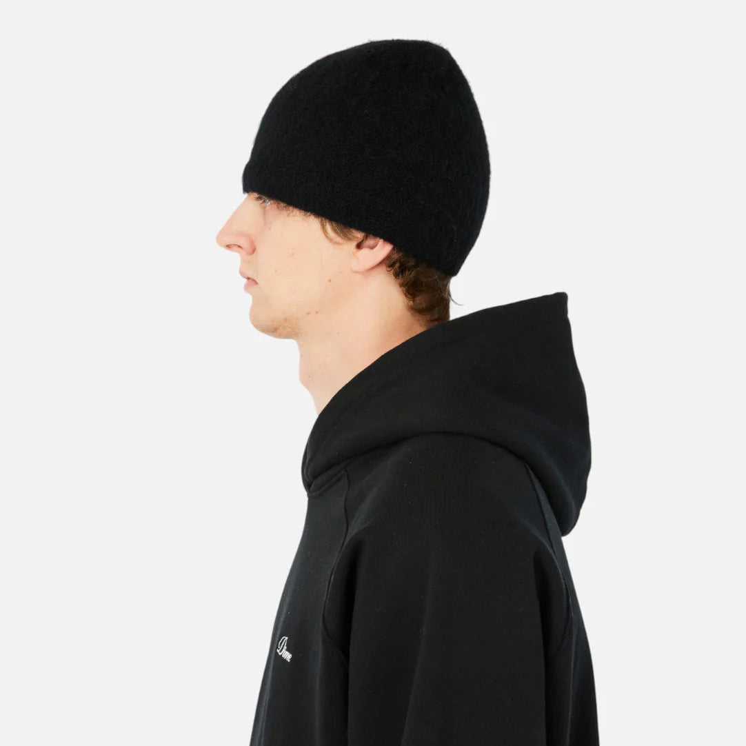 Person wearing a black hoodie and beanie on a white background