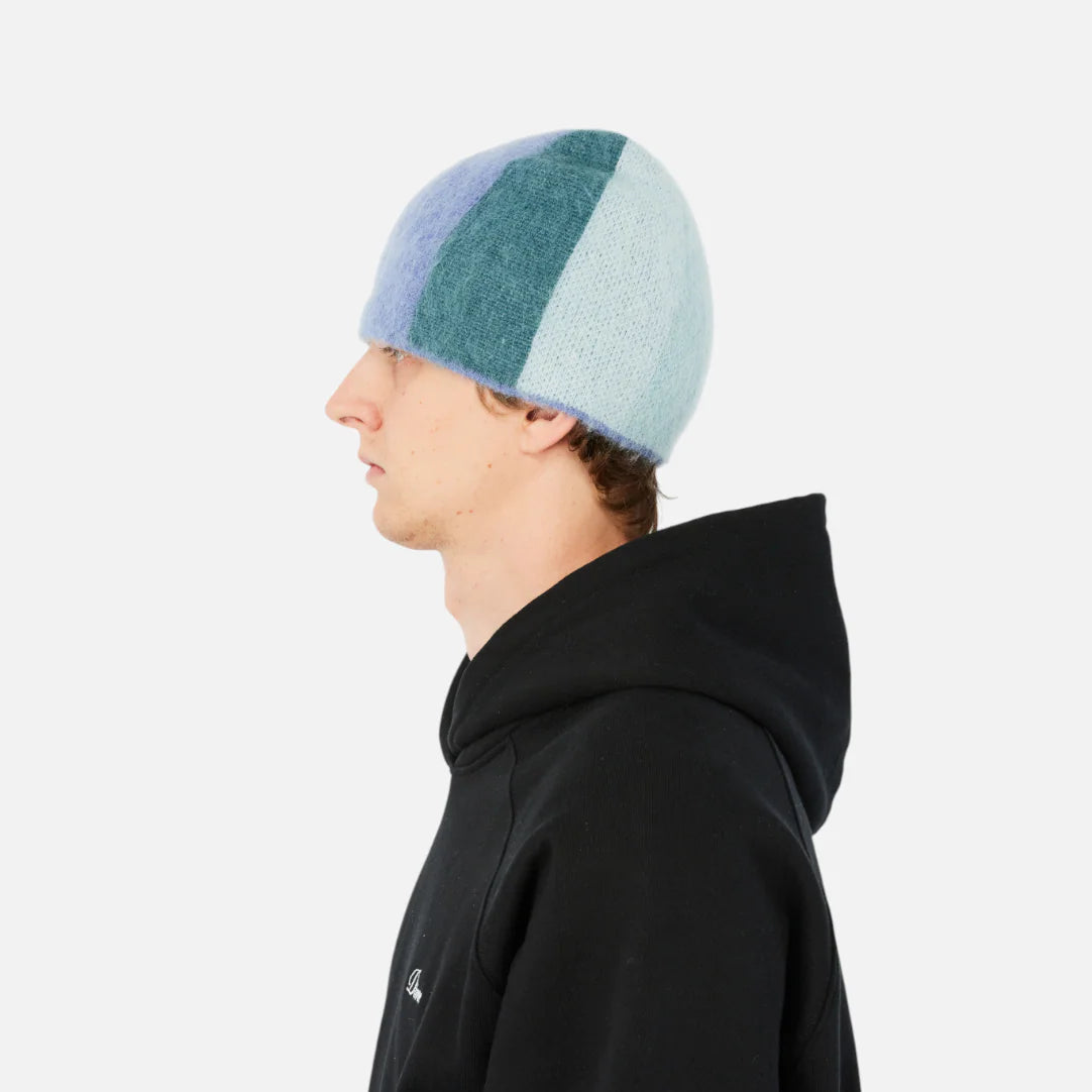 Person wearing a black hoodie and a multicolored beanie on a white background