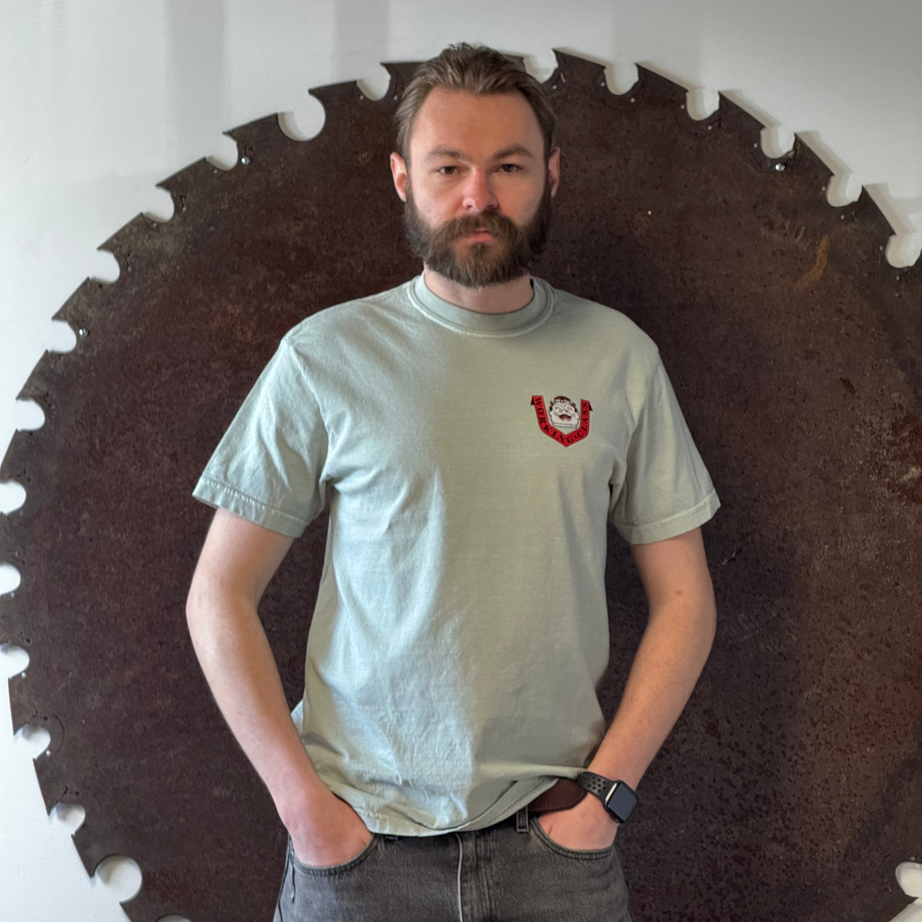 Man standing in front of a large circular saw blade on a white wall