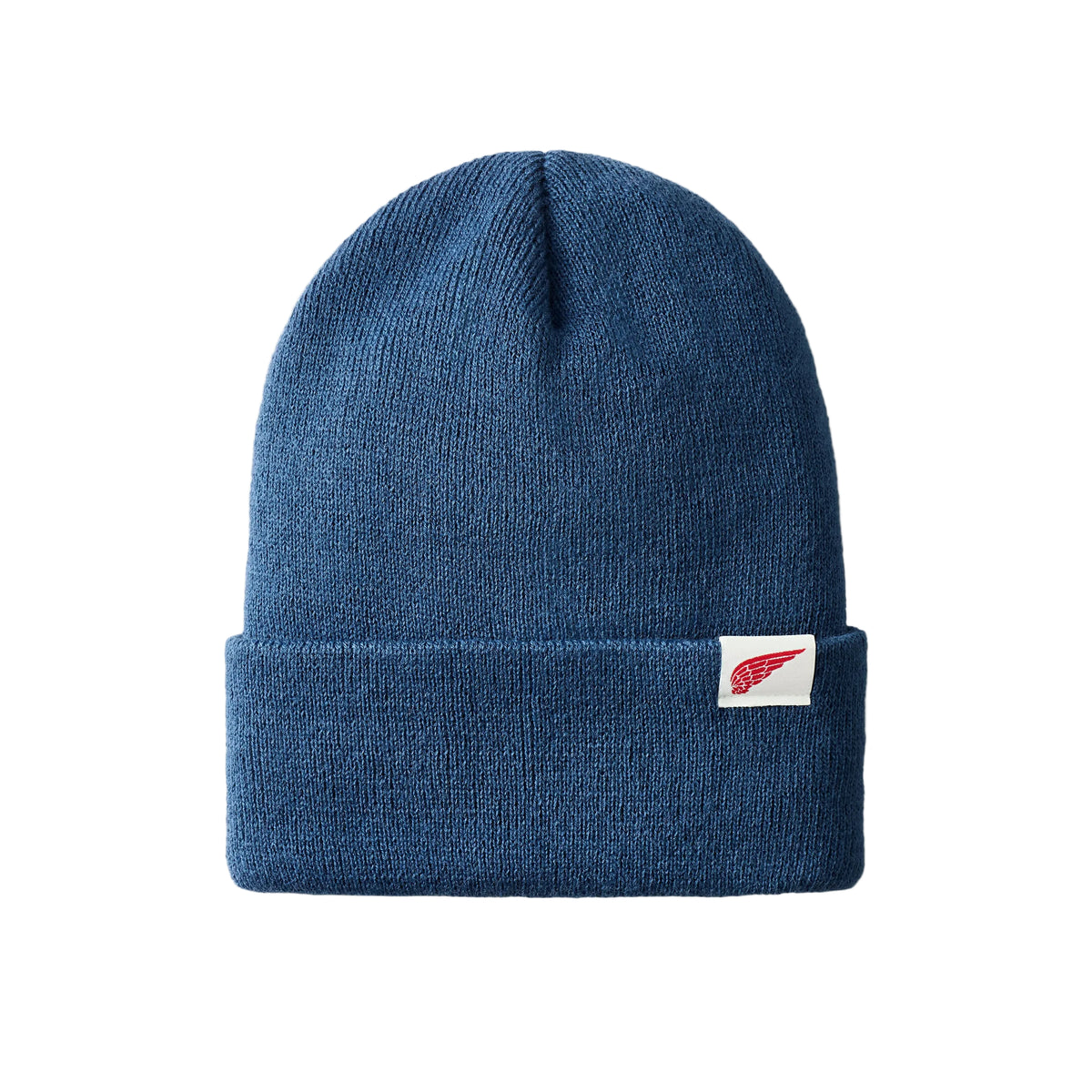 A blue knit cuffed beanie hat with a small white rectangular brand tag featuring a red wing logo on the front cuff, set against a light gray background.