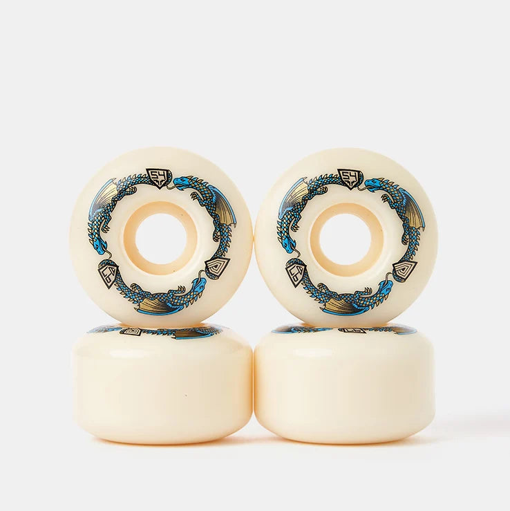 Four cream-colored skateboard wheels stacked in a 2x2 grid, featuring blue and black wave graphics and a small black brand logo on each wheel face, set against a clean white background.