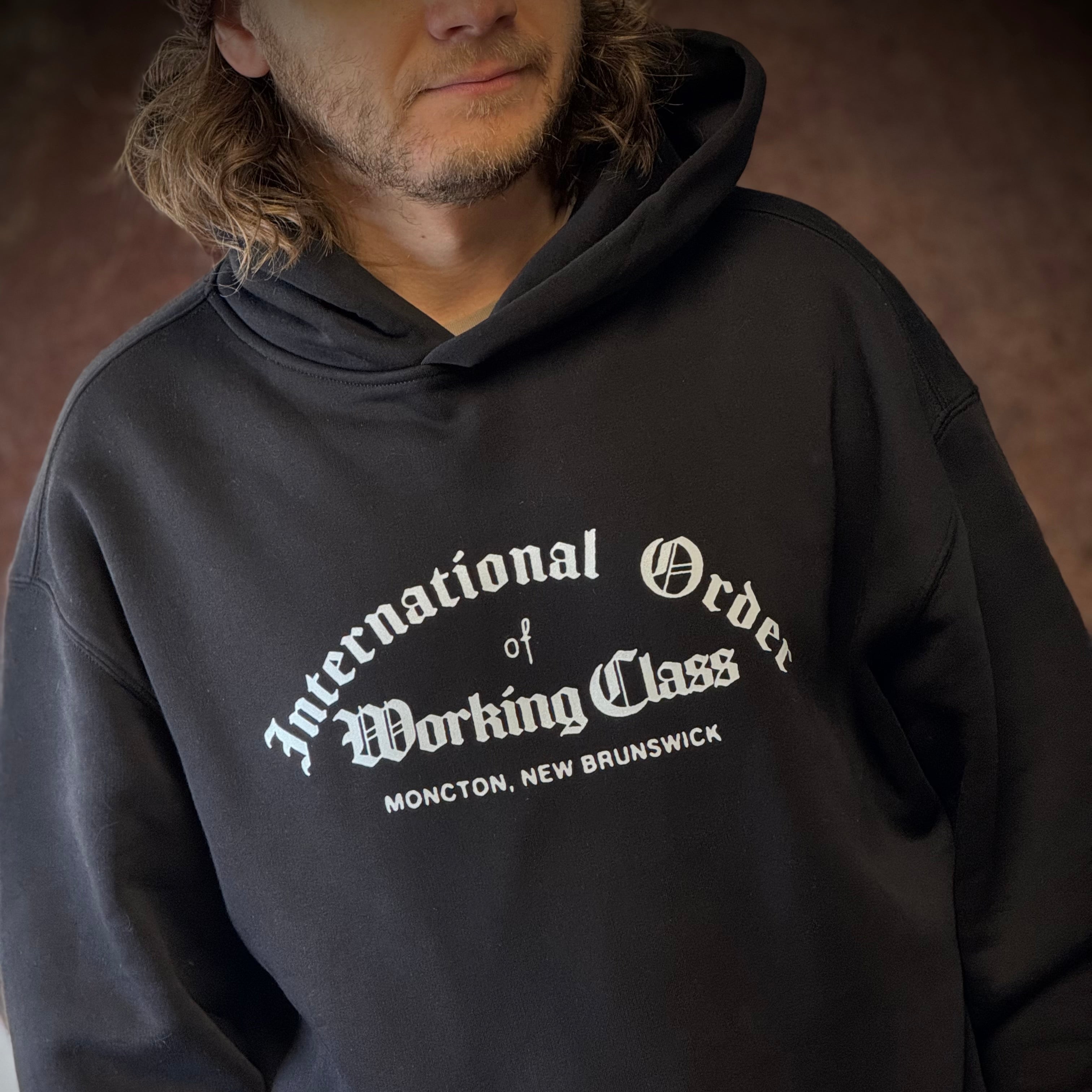Person wearing a black hoodie with white text on a brown background