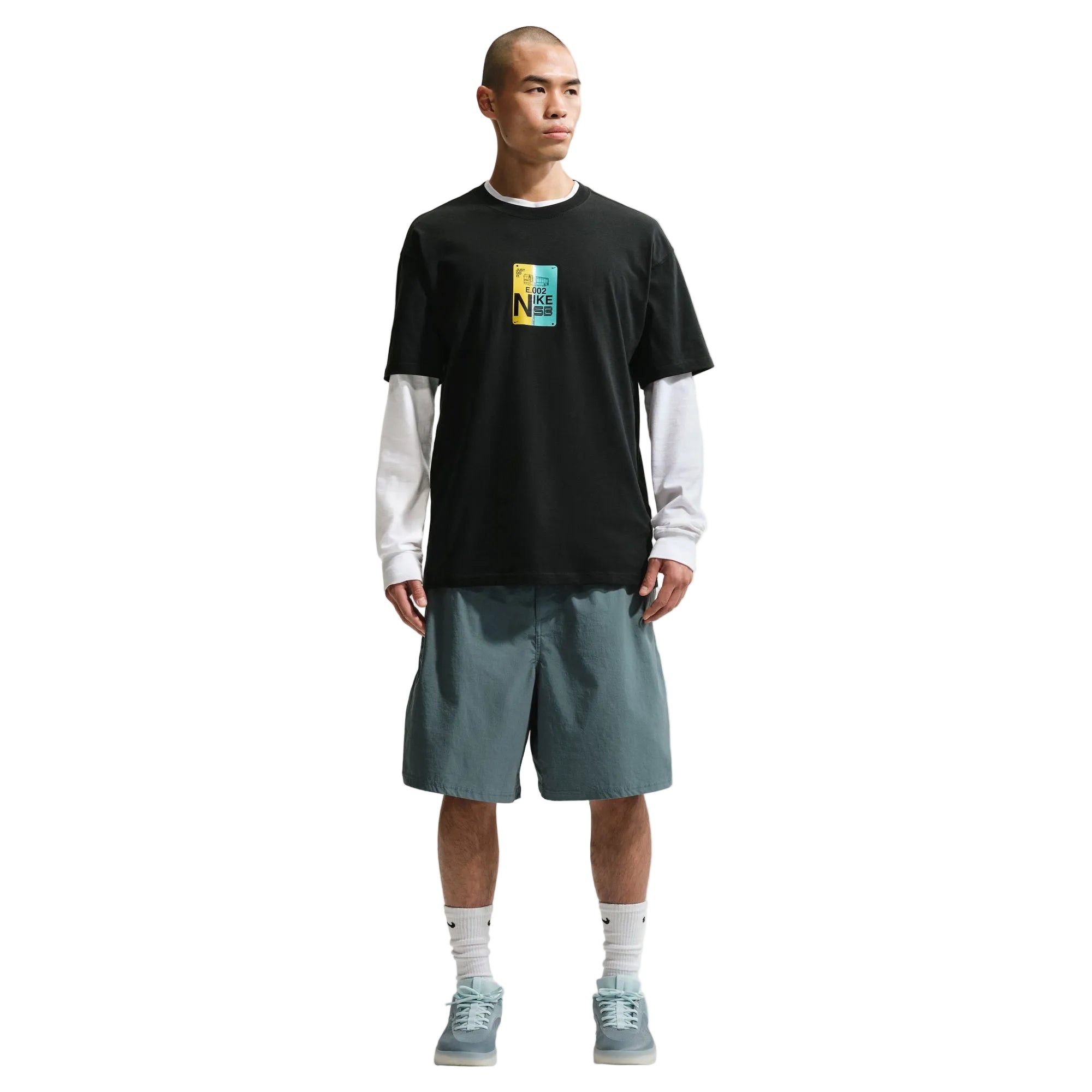 Man wearing a black t-shirt with a colorful graphic and gray shorts on a white background