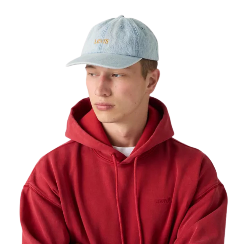 A young man wearing a light blue denim baseball cap with 'LEVI'S' embroidered in gold on the front, paired with a red hoodie, shown against a plain white background.