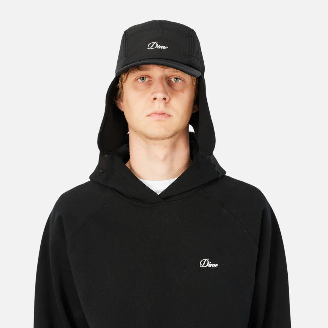 Person wearing a black hoodie and cap with a logo on a white background
