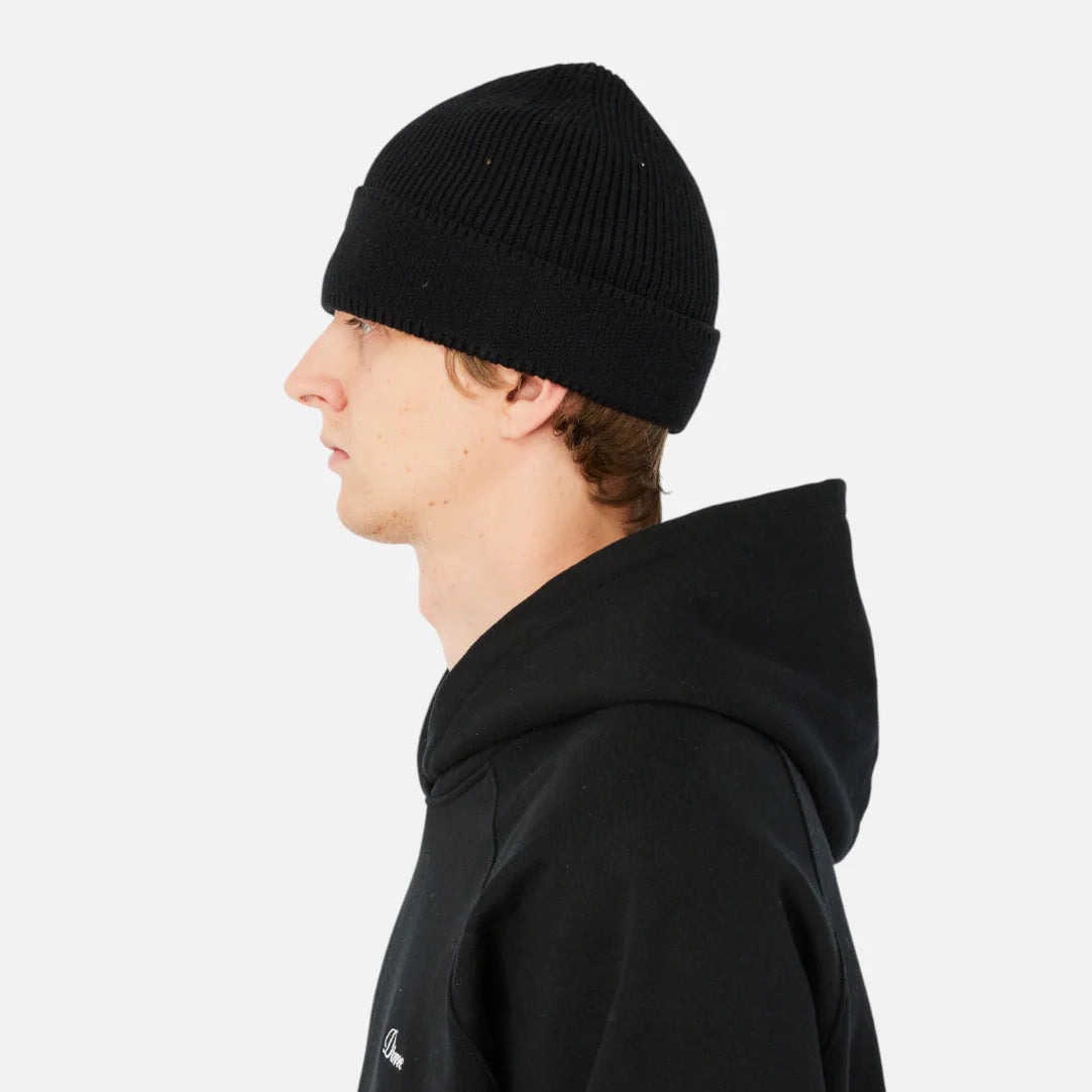 Person wearing a black hoodie and beanie on a white background