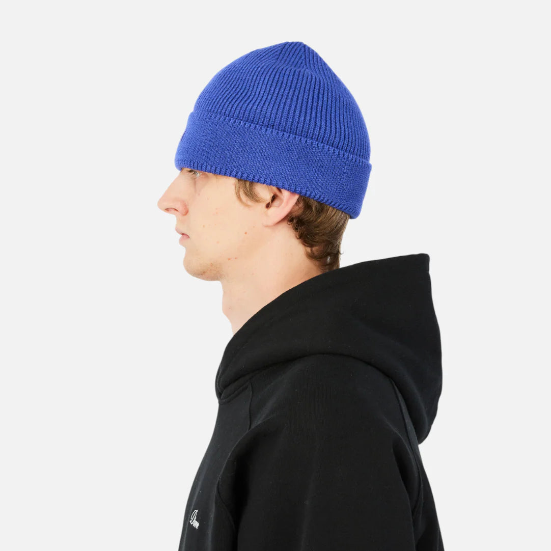 Person wearing a blue beanie and black hoodie on a white background