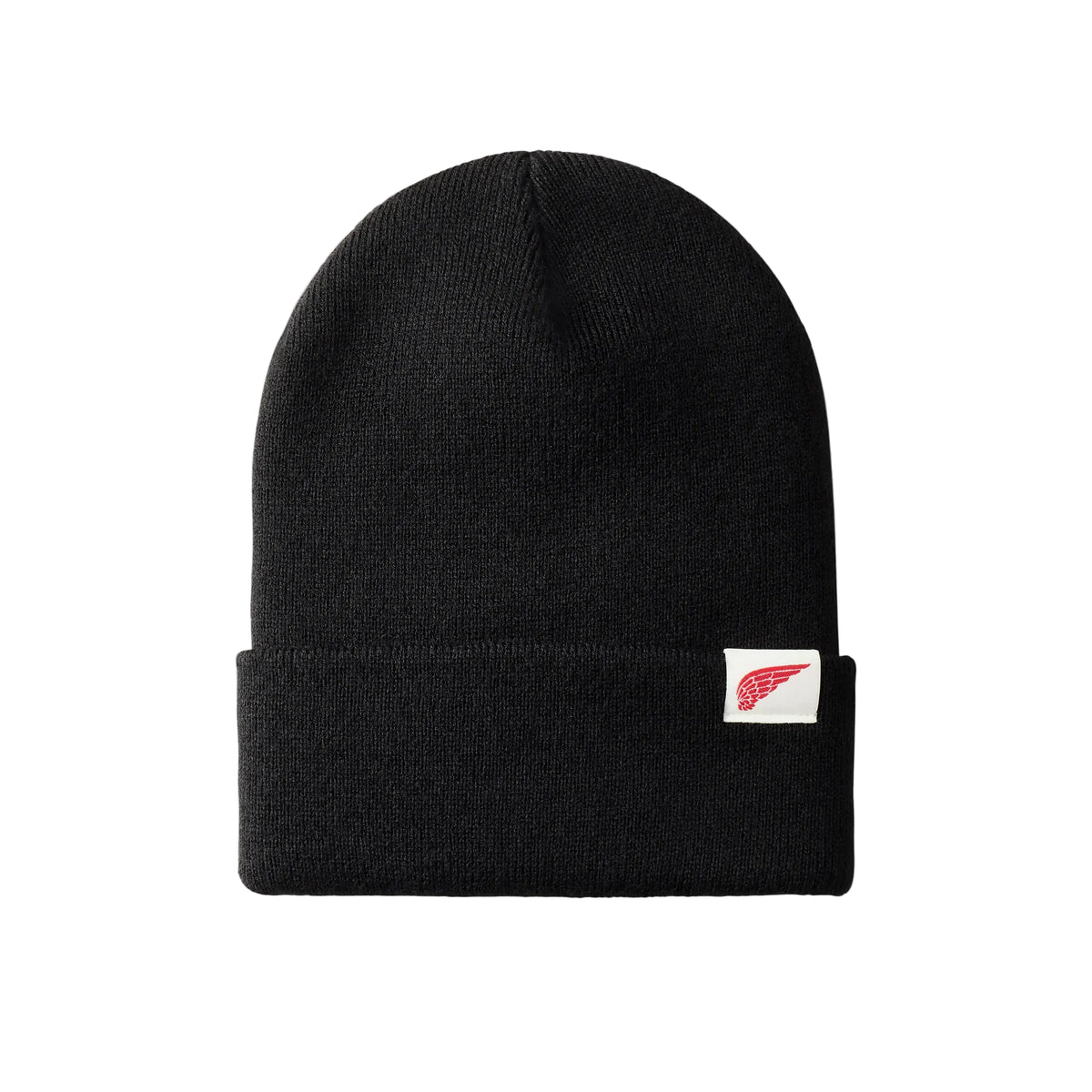 A black knit beanie hat with a folded cuff, featuring a small white square patch on the side with a red wing logo, shown against a light gray background.