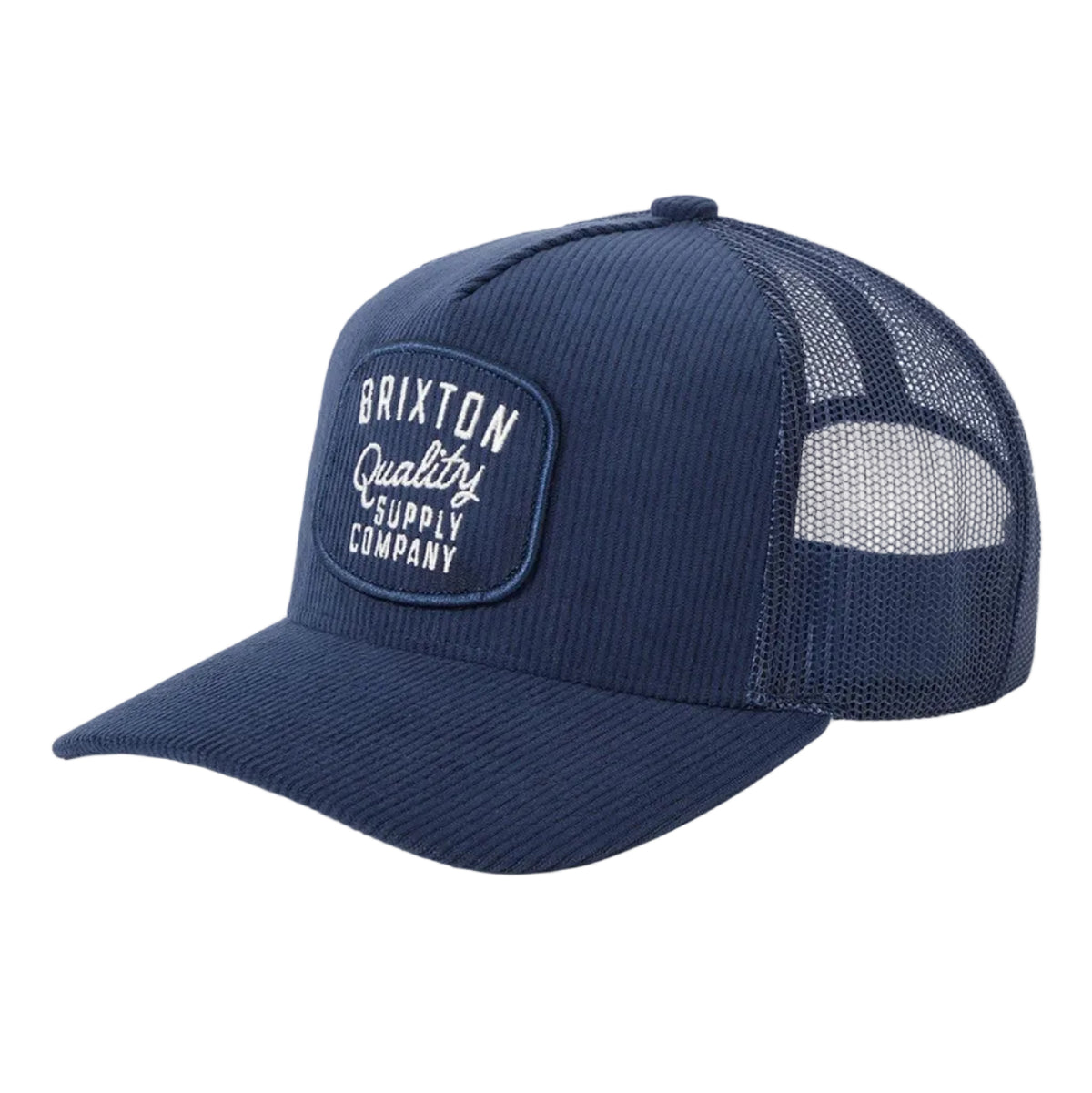 A navy blue trucker cap with a curved brim, featuring a front patch that reads 'Brixton Quality Supply Company' in white text, set against a clean light gray background.