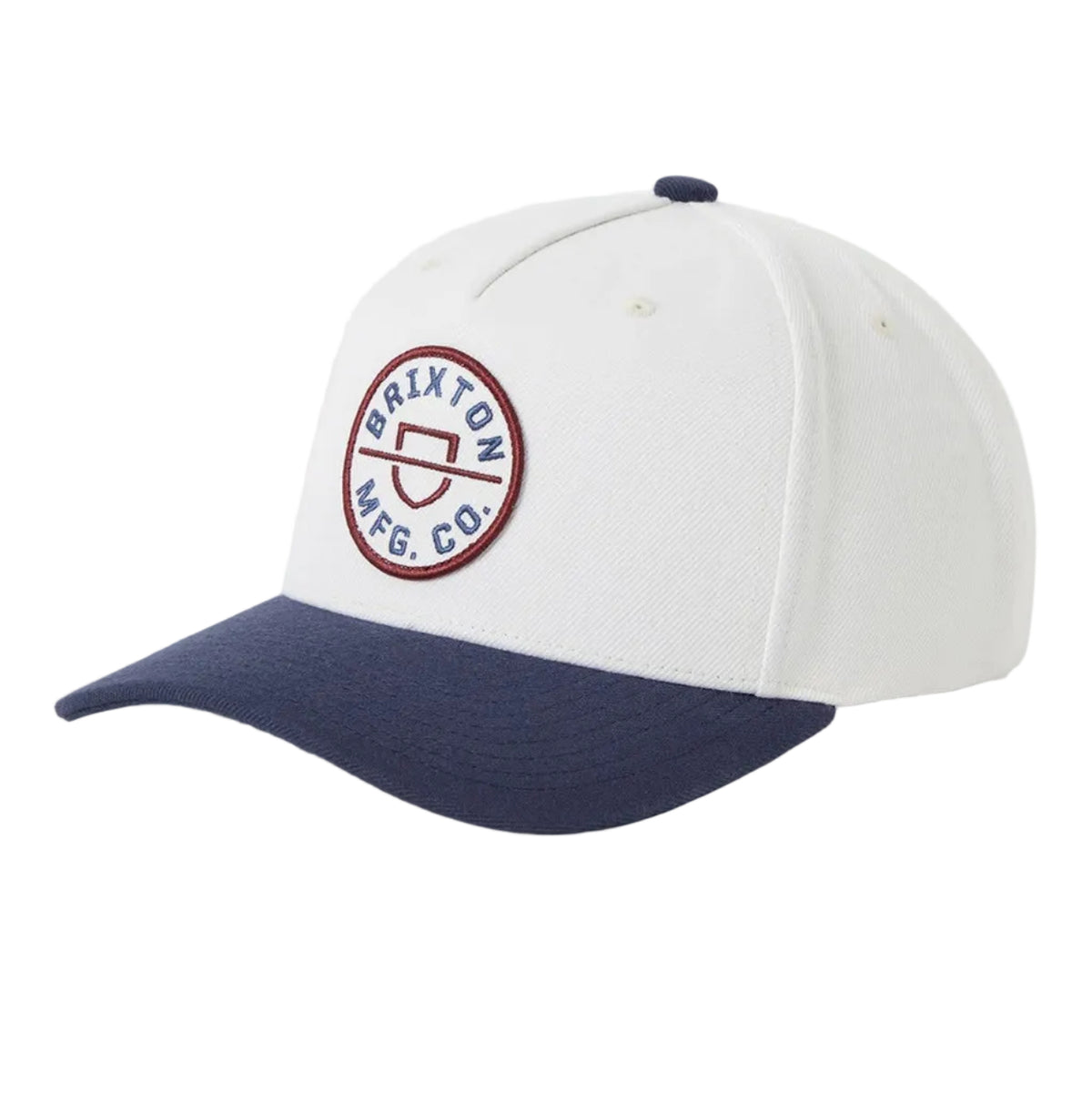 A baseball cap with a white crown and a navy blue curved brim, featuring a circular embroidered logo on the front that reads 'Brixton MFG.co"